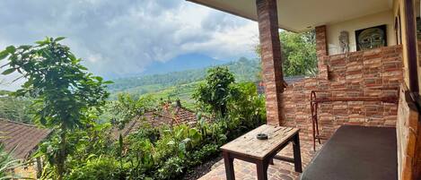 A balcony with a stone floor, a wooden table, and a cushioned bench.