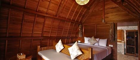 Una cabaña de madera con una cama, una mesita y una lámpara colgante.