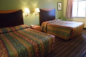 A hotel room with two beds, a nightstand, two wall lamps, and a window with curtains.