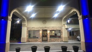 A building entrance with a brick facade, a clock, and multiple lights. - Executive Inn Odessa (Odessa)