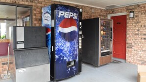 A vending machine area with a Pepsi-branded machine, a smaller ice dispenser, and a red door. - Executive Inn Odessa (Odessa)