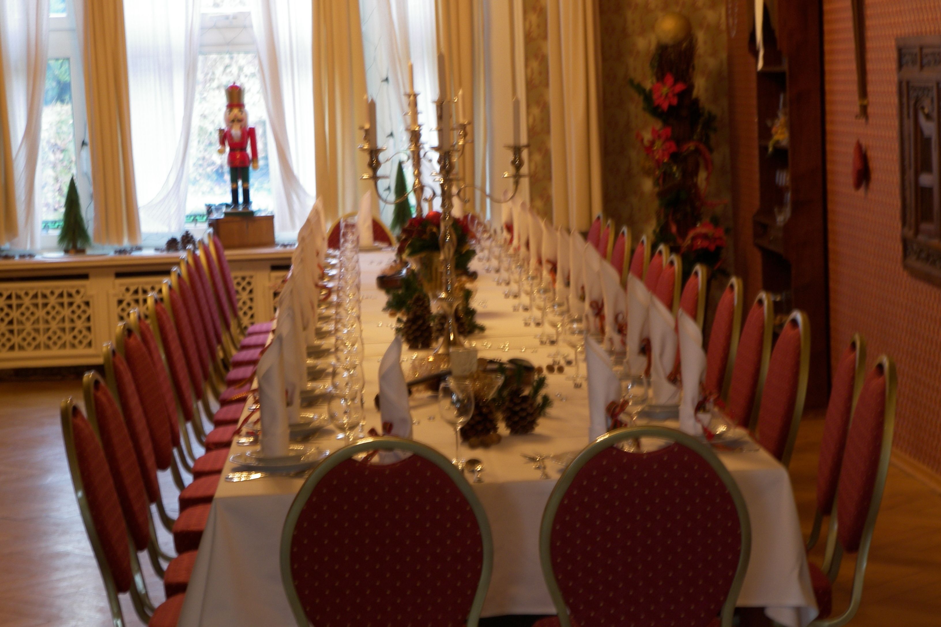 A long dining table set with red chairs, candles, and floral centerpieces.