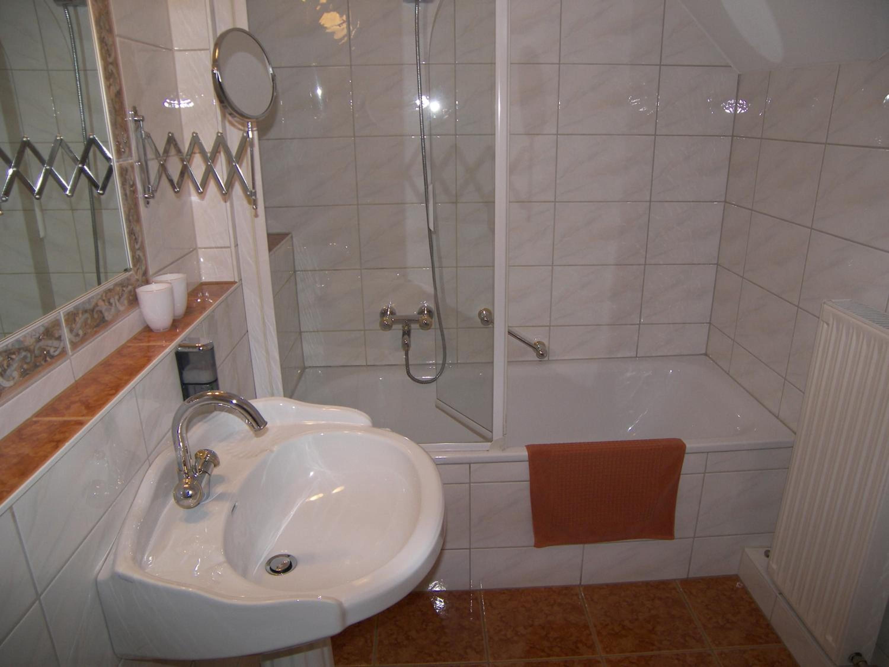 Ein Badezimmer mit Waschbecken, Spiegel, Dusche und Badewanne.