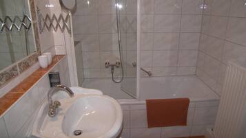 Ein Badezimmer mit Waschbecken, Spiegel, Dusche und Badewanne.
