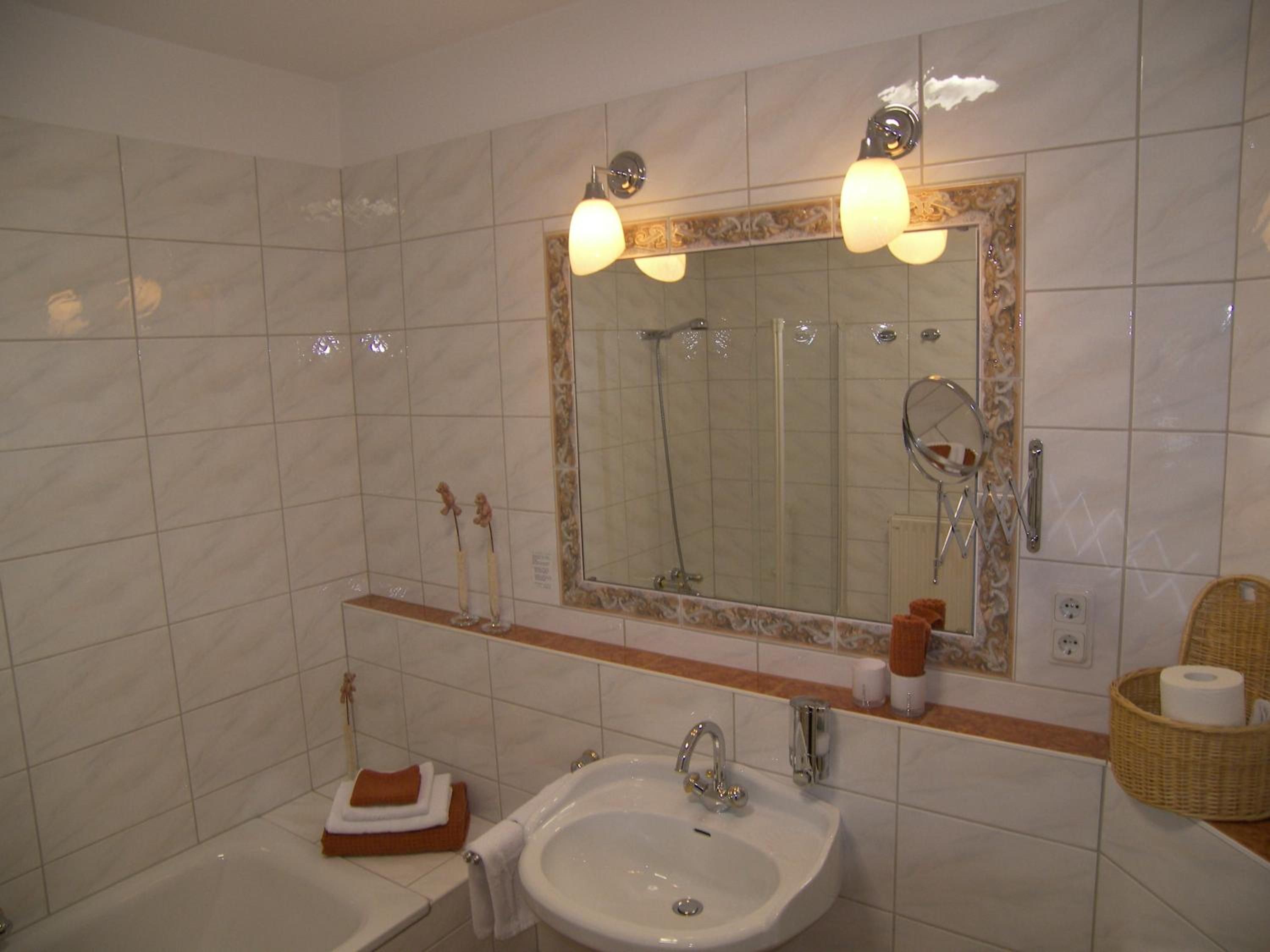 Ein Badezimmer mit Waschbecken, Spiegel, Dusche und Handtuchhalter.
