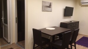 A small, modern room with a wooden table and chairs, a flat-screen TV mounted on the wall, and a small cabinet. - Haus Alpenblick Mölltal (Flattach)