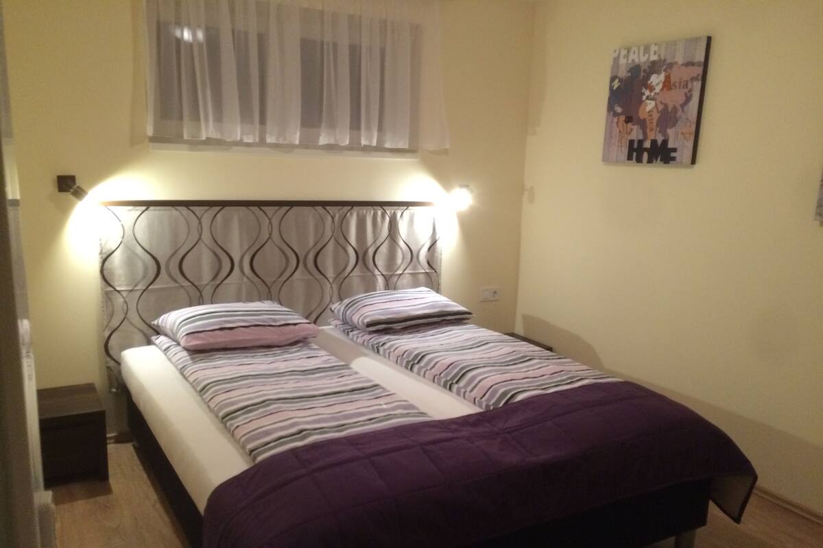 Cama doble con cabecera, dos almohadas y una manta púrpura.