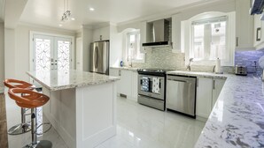 A modern kitchen with white cabinetry, stainless steel appliances, and a marble countertop. - Entire Bungalow 5 Bedrooms (Markham)