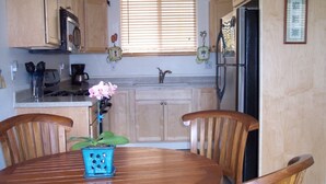 A kitchen with wooden cabinets, a black refrigerator, a sink, and a window with blinds.