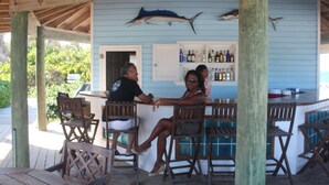 Une terrasse en bois avec un coin bar comprenant deux chaises et un comptoir.
