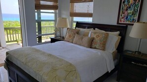 Une chambre à coucher avec un lit, deux tables de chevet, une fenêtre donnant sur un beau paysage et un tableau accroché au mur.