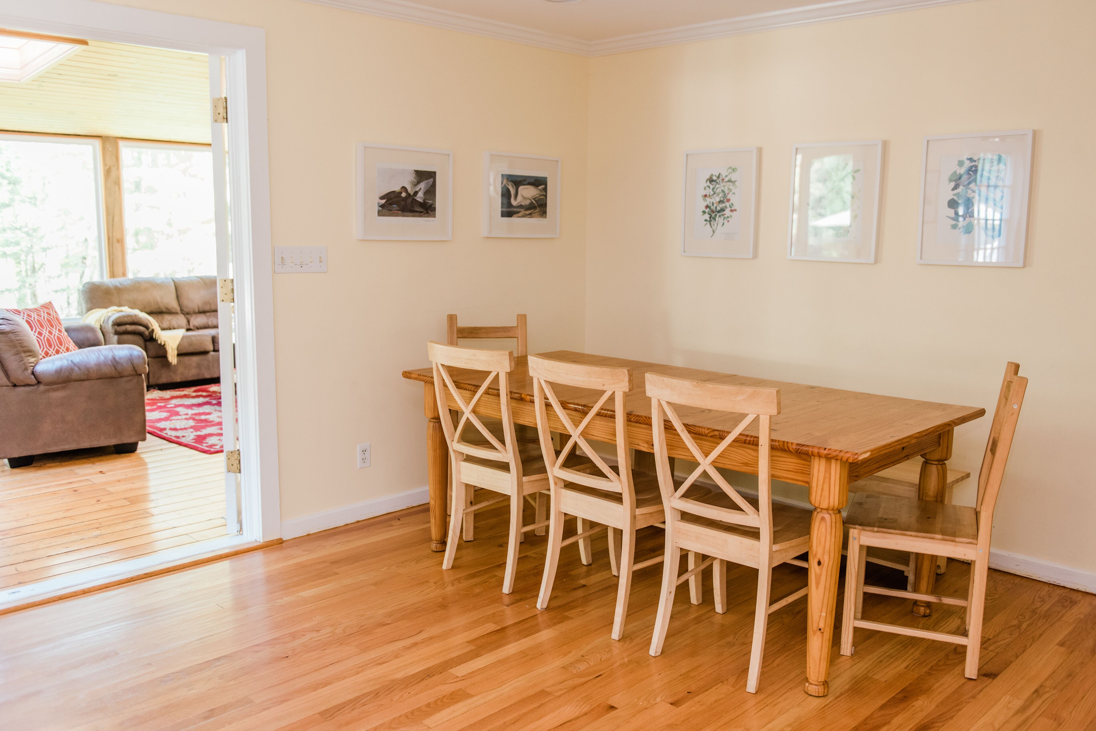 Un coin repas avec une table et des chaises en bois, un canapé et des tableaux encadrés au mur.