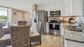 Een moderne keuken met roestvrijstalen apparatuur, witte kasten en een eethoek met gestreepte stoelen.