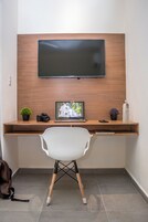 Un espacio de trabajo moderno con un escritorio de madera, una computadora portátil, una cámara y un televisor montado en la pared.