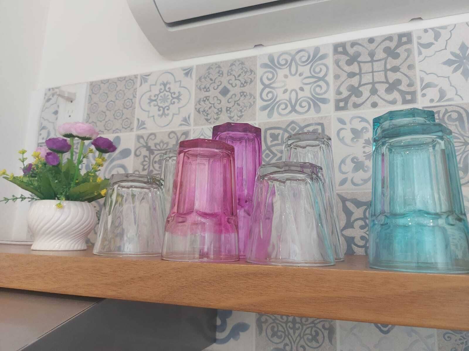 En hylde med forskellige glasflasker og en potteplante med blomster.