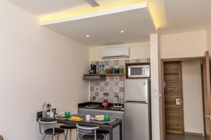 A compact kitchen with a dining area, featuring a microwave, refrigerator, and a coffee maker.