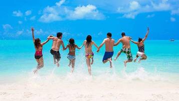 A group of people jumping into the sea on a beach.