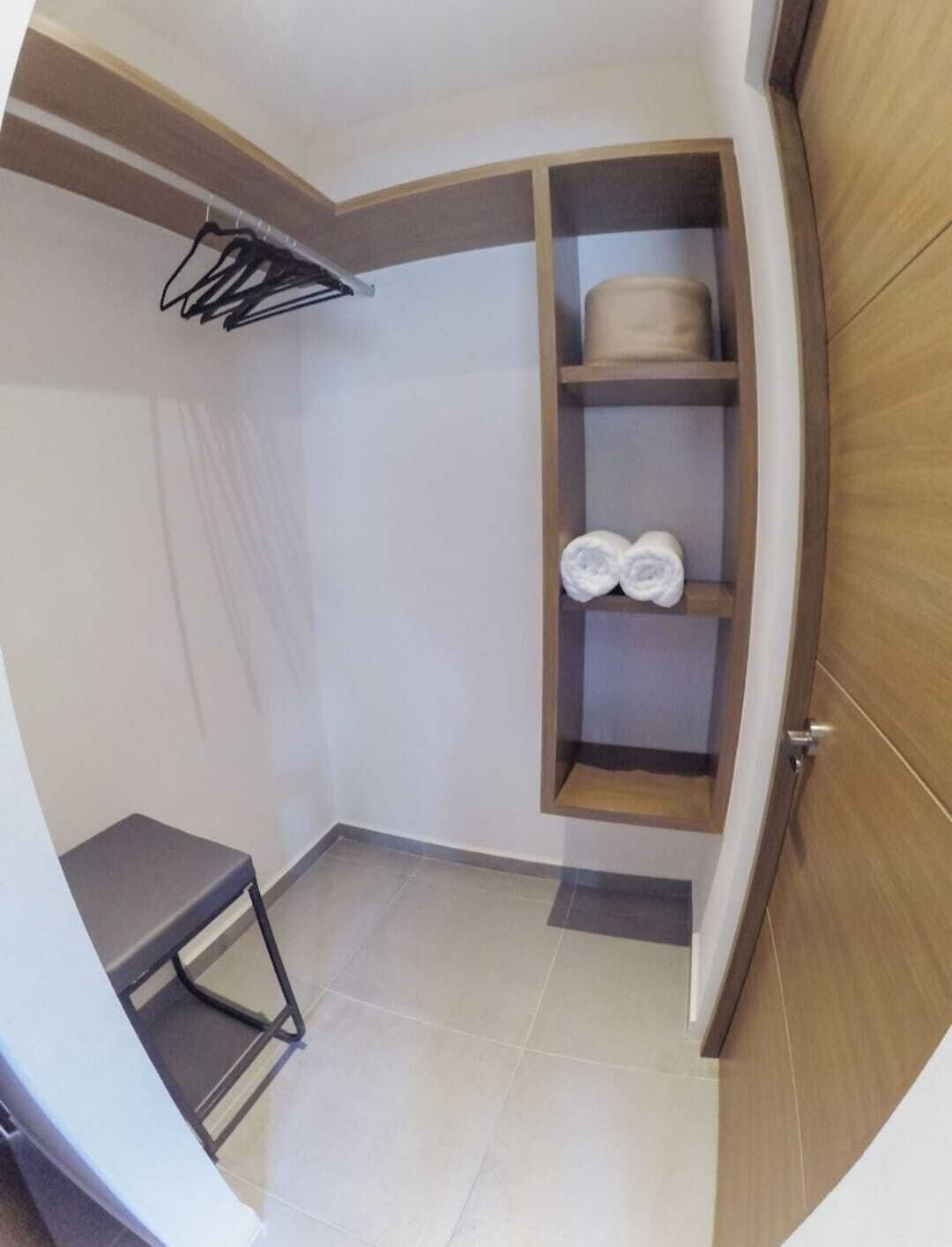 Une petite salle de bain moderne avec un meuble-lavabo en bois, un porte-serviettes et une étagère où sont rangées les serviettes.