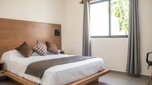 Una camera da letto moderna con una testiera in legno, un letto grande con molti cuscini, un comodino con una lampada e una finestra con tende.