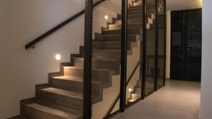 Una scala moderna con ringhiera in metallo e design a rete, che porta a un'area di sbarco con una porta.