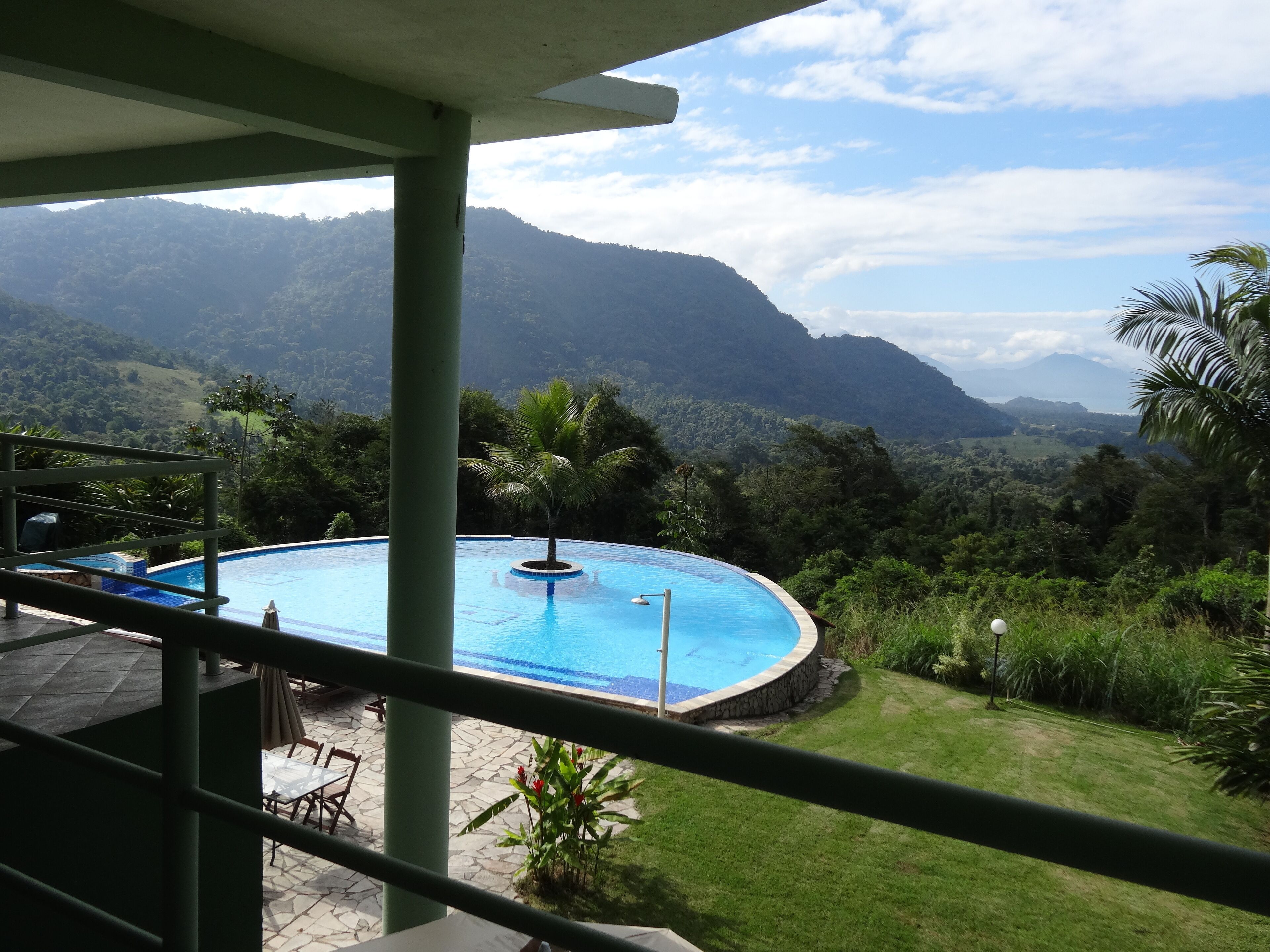 Une piscine avec vue sur les montagnes, entourée de verdure et dotée d’une terrasse en pierre.