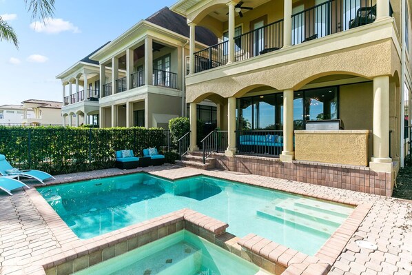 A two-story building with a swimming pool, outdoor seating, and a covered patio area.