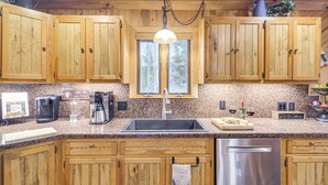 A kitchen with wooden cabinets, granite countertops, a stainless steel dishwasher, and a coffee maker. - 2 Mi to Rocky Mountain Nat'l Park: Cabin w/ Views (Grand Lake)