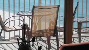 Un balcón con mesa y sillas, con vista a la playa.
