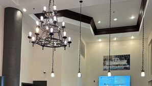 Un área de recepción con una araña, una pantalla digital y un cartel que indica 'Shores of Panama Exclusive Onsite Management'.