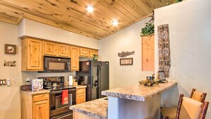 A kitchen with wooden cabinets, a microwave, a refrigerator, and a granite countertop. - 3 Mi to Fool Hollow Lake: Romantic Show Low Cabin (Show Low)