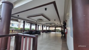 Un espace extérieur abrité, avec des chaises et des tables, un extincteur, et une vue sur les bâtiments en arrière-plan.