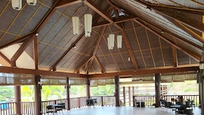 Un espace extérieur abrité, doté d’un haut plafond, de poutres en bois et de luminaires suspendus.