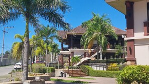 A multi-story building with a central staircase, surrounded by palm trees and greenery. - Fully furnished with Self check in, Pool & Netflix  at One Oasis Condominium CDO (Cagayan de Oro)