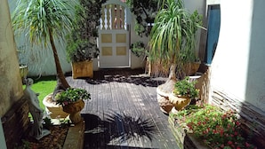 Ein Innenhof mit Holzdeck, Blumentöpfen und einer Statue.