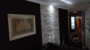 Ein Zimmer mit einem gerahmten Zertifikat an der Wand, einer Ziegelwand und einer Tür mit einem Bierlogo.