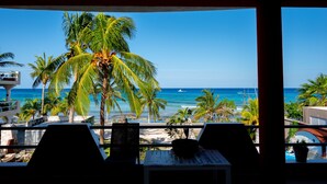 Un balcón con vista a la playa, palmeras y el océano.