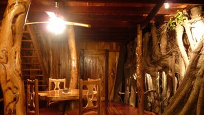Un coin repas rustique, avec des meubles en bois et un mur décoré avec un tronc d’arbre.
