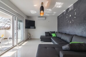 Relax in this stylish living room with a large sofa, flat-screen TV, and a beautiful view.