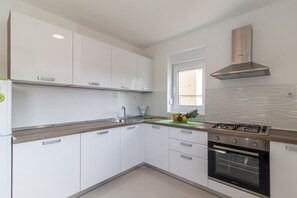 Enjoy cooking in this well-lit kitchen with a stainless steel range hood and oven.