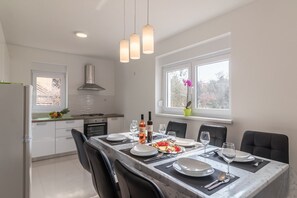 Enjoy meals in the kitchen and dining area with a stainless steel range hood and a marble-top table.