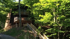 A cabin with a wooden deck and stairs leading to a balcony.