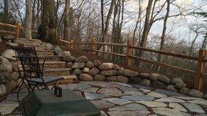 A stone patio with a grill, a table, and chairs.