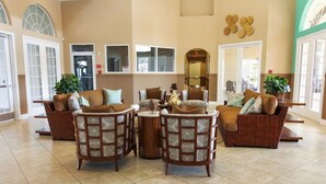 A spacious lobby with wicker furniture, large windows, and a high ceiling.