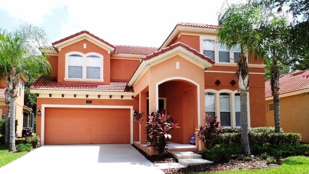 A two-story house with a red-tiled roof, a garage, and a well-maintained lawn.