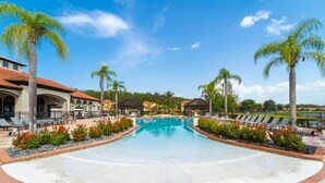 A swimming pool surrounded by palm trees and lounge chairs, with a building in the background.