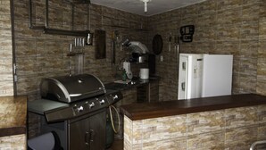 A kitchen with a built-in grill, a coffee maker, and a refrigerator. - Comfortable beach house with pool, terrace, barbecue, 300 m from the beach. (São Sebastião)
