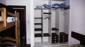 A bedroom with a wooden bunk bed, a white wardrobe with multiple shelves and drawers, and a bed with a floral bedspread. - Comfortable beach house with pool, terrace, barbecue, 300 m from the beach. (São Sebastião)