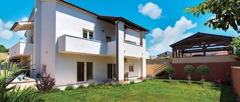 A two-story house with a flat roof, a balcony, and a covered patio area.