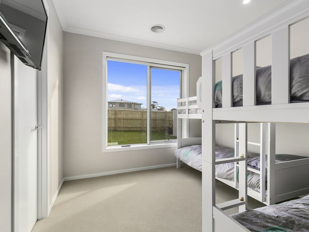 A bedroom with bunk beds, a large window, and a view of the backyard.