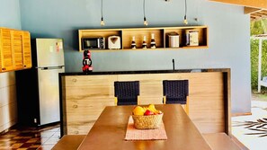 Une cuisine moderne avec un îlot central en bois, un four à micro-ondes, un grille-pain et une machine à café placés sur une étagère.